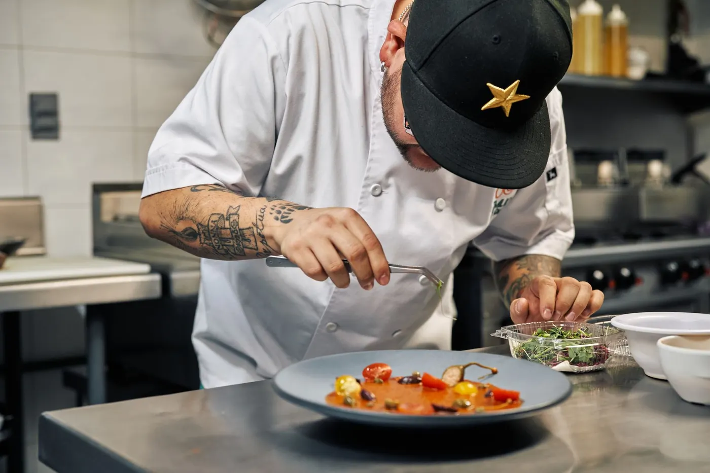 Chef concentré dressant une assiette dans une cuisine de restaurant.