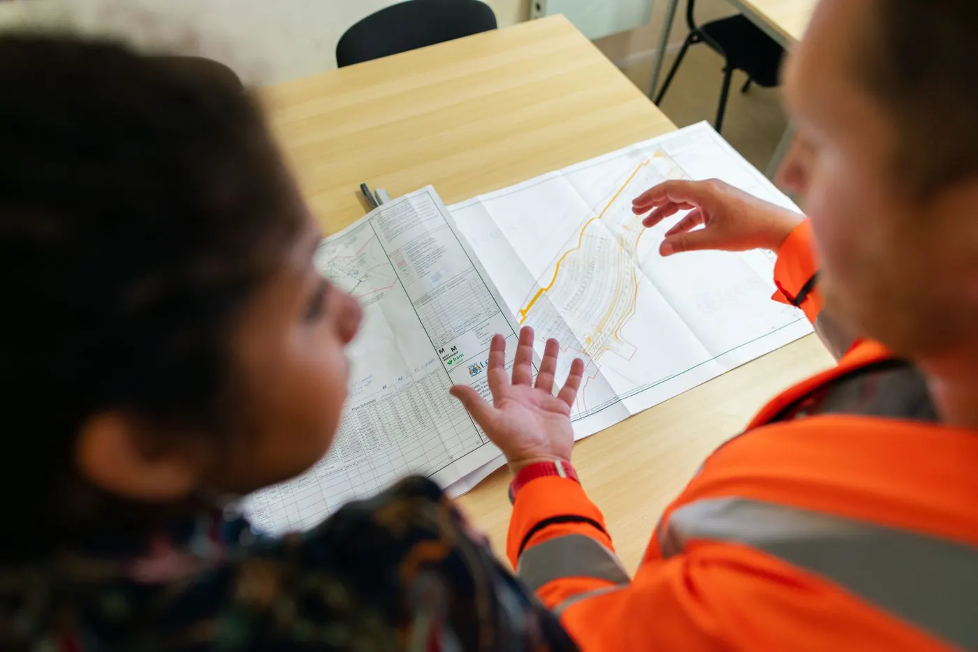 Deux professionnels planifiant une stratégie sur un plan.
