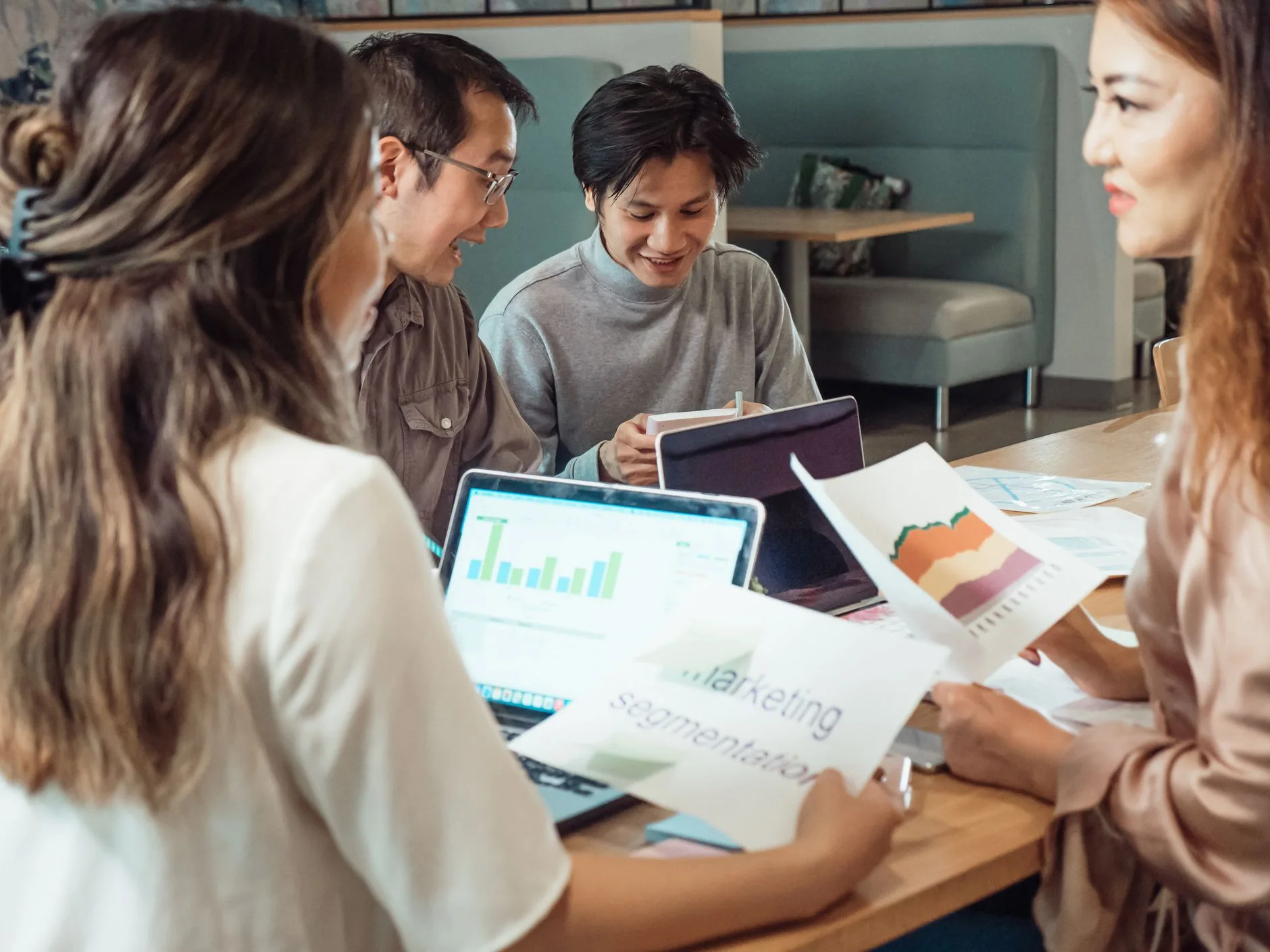 Équipe marketing comparant des visuels imprimés et un tableau de bord affiché sur un ordinateur portable
