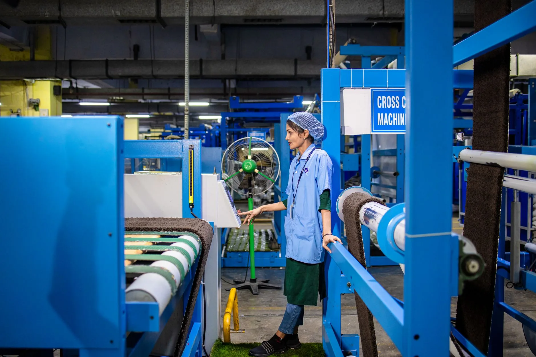 Opératrice surveille le fonctionnement d'une machine de production dans un atelier industriel