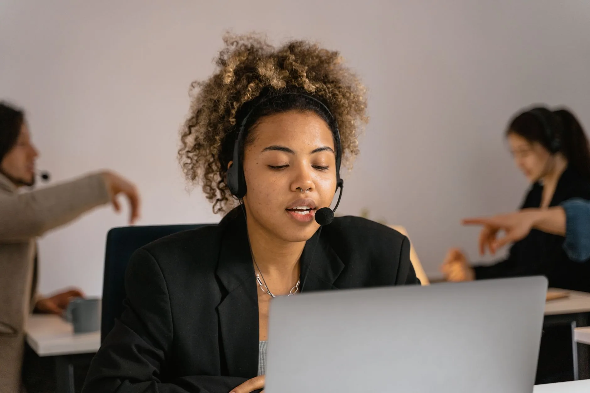Conseillère avec micro-casque traite une demande client sur son ordinateur portable en open space