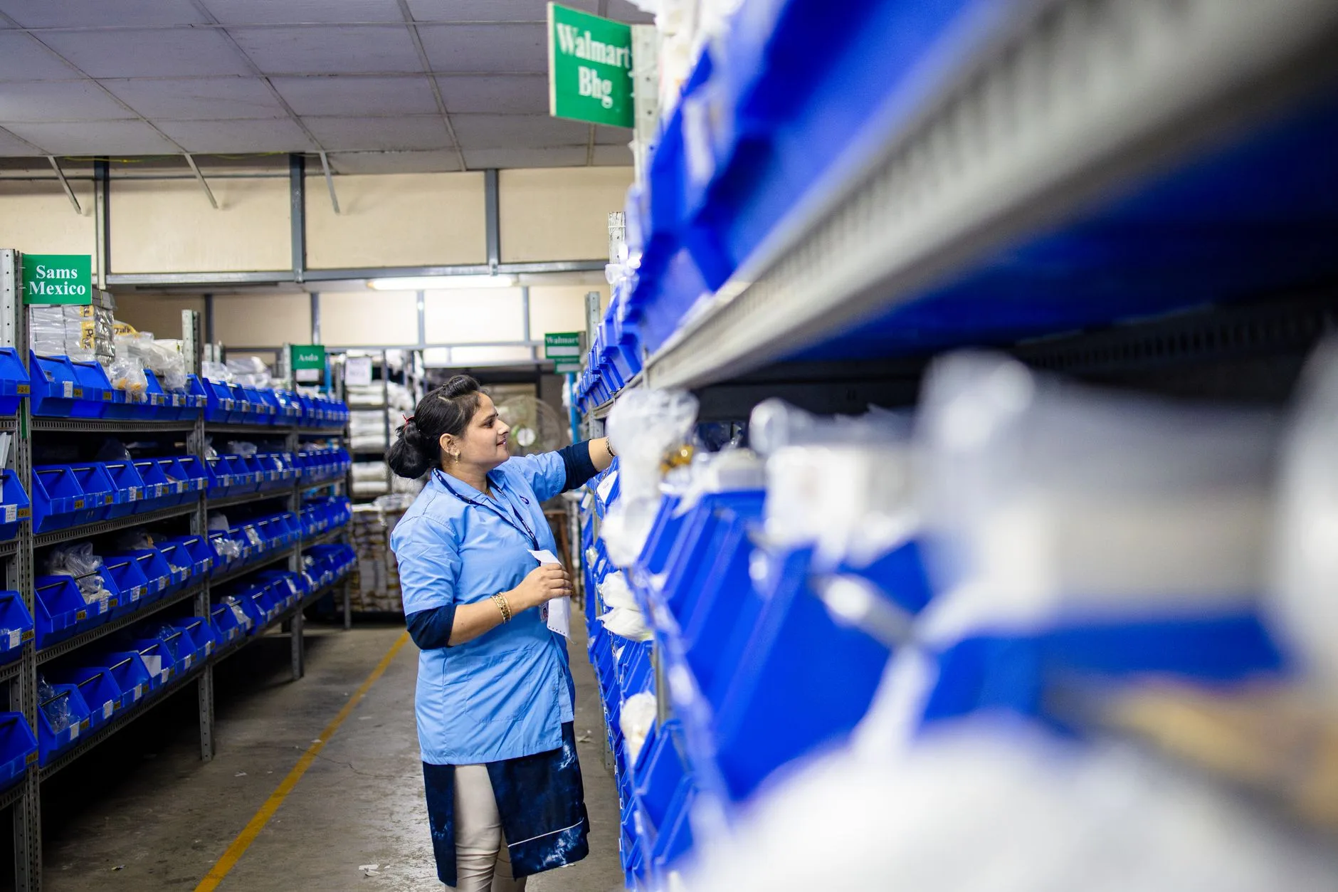 Opératrice range des pièces détachées dans les bacs étiquetés du magasin d'une usine