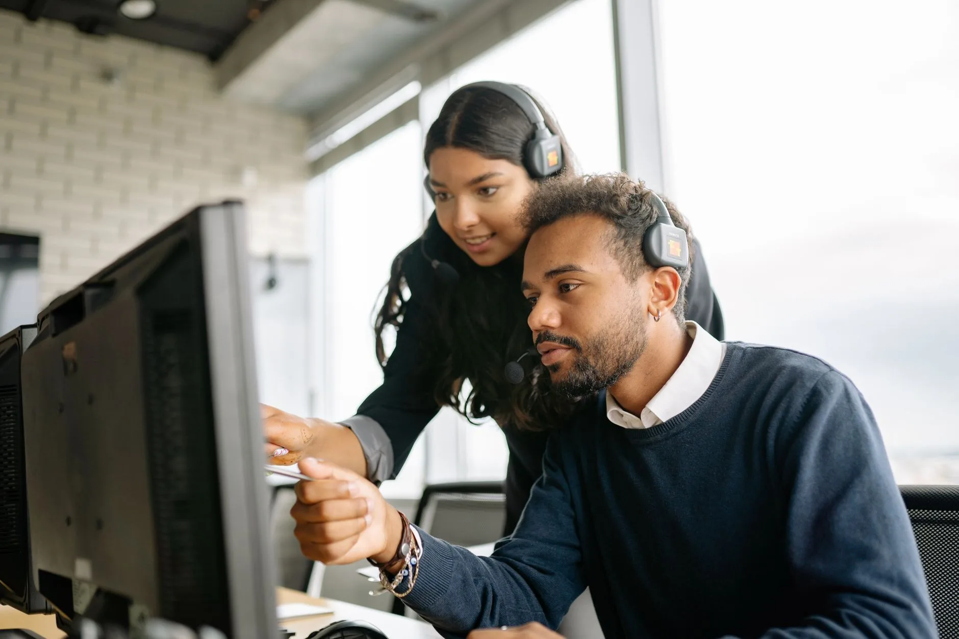 Deux conseillers du service client avec casque audio analysent une demande sur un écran d'ordinateur