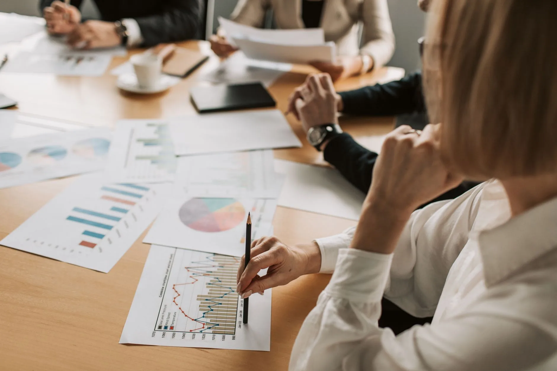 Équipe réunie autour d'une table de travail compare plusieurs graphiques de résultats imprimés