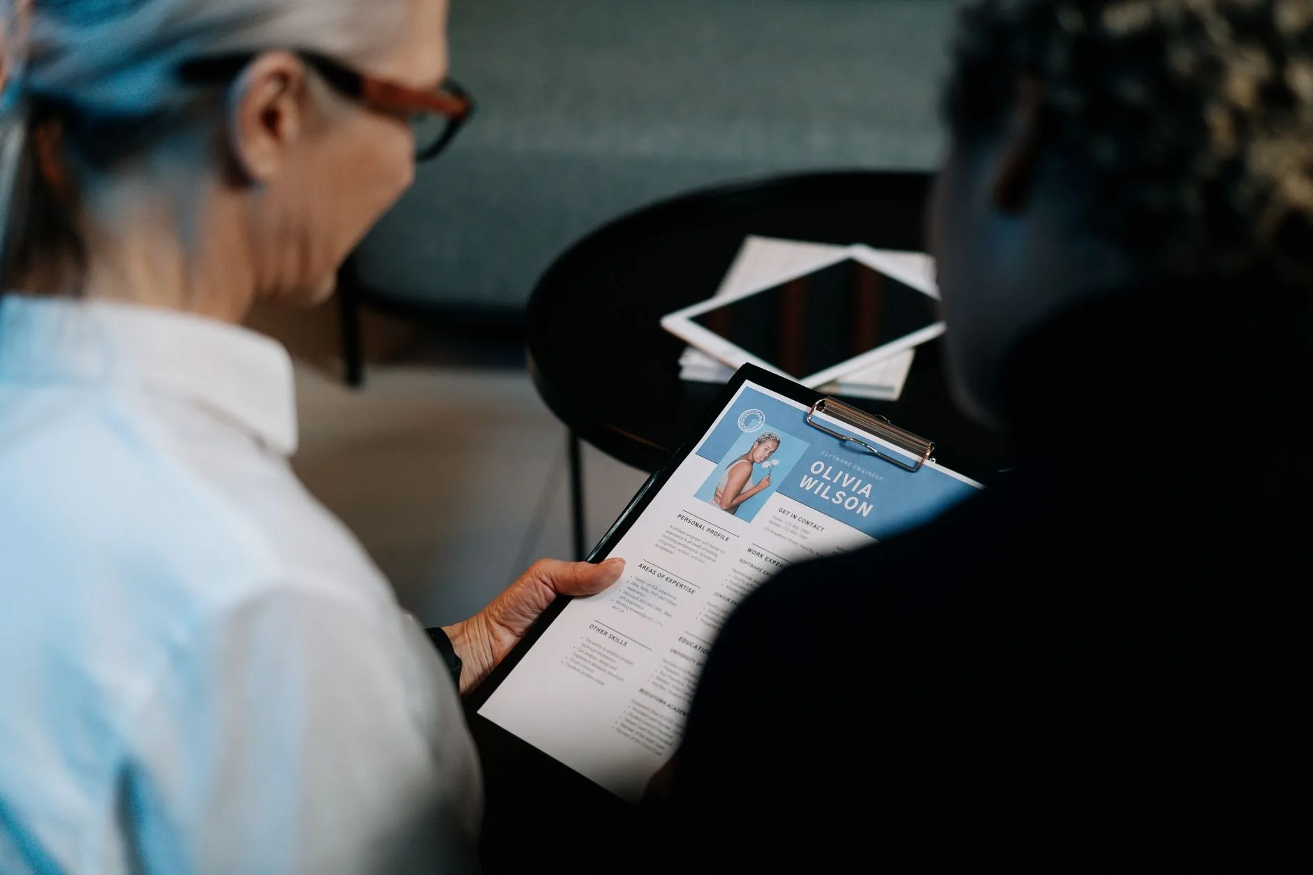 Deux recruteurs examinent un CV imprimé sur un porte-bloc pendant un entretien en entreprise
