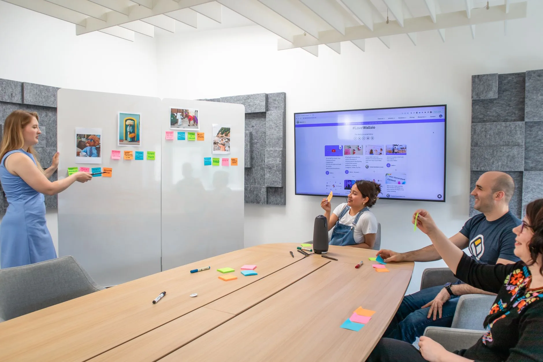 Atelier collaboratif en salle de réunion avec des post-it collés au mur et un écran de partage