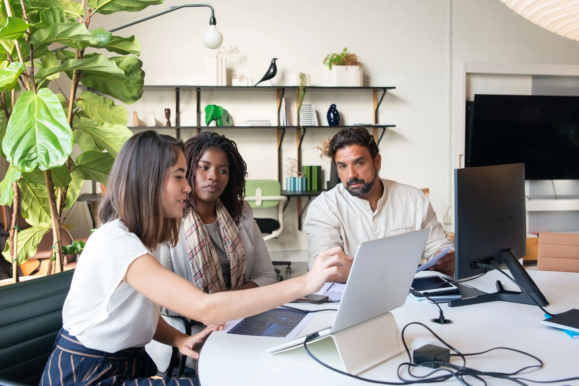 Trois collaborateurs comparent des solutions logicielles sur un ordinateur portable dans un bureau