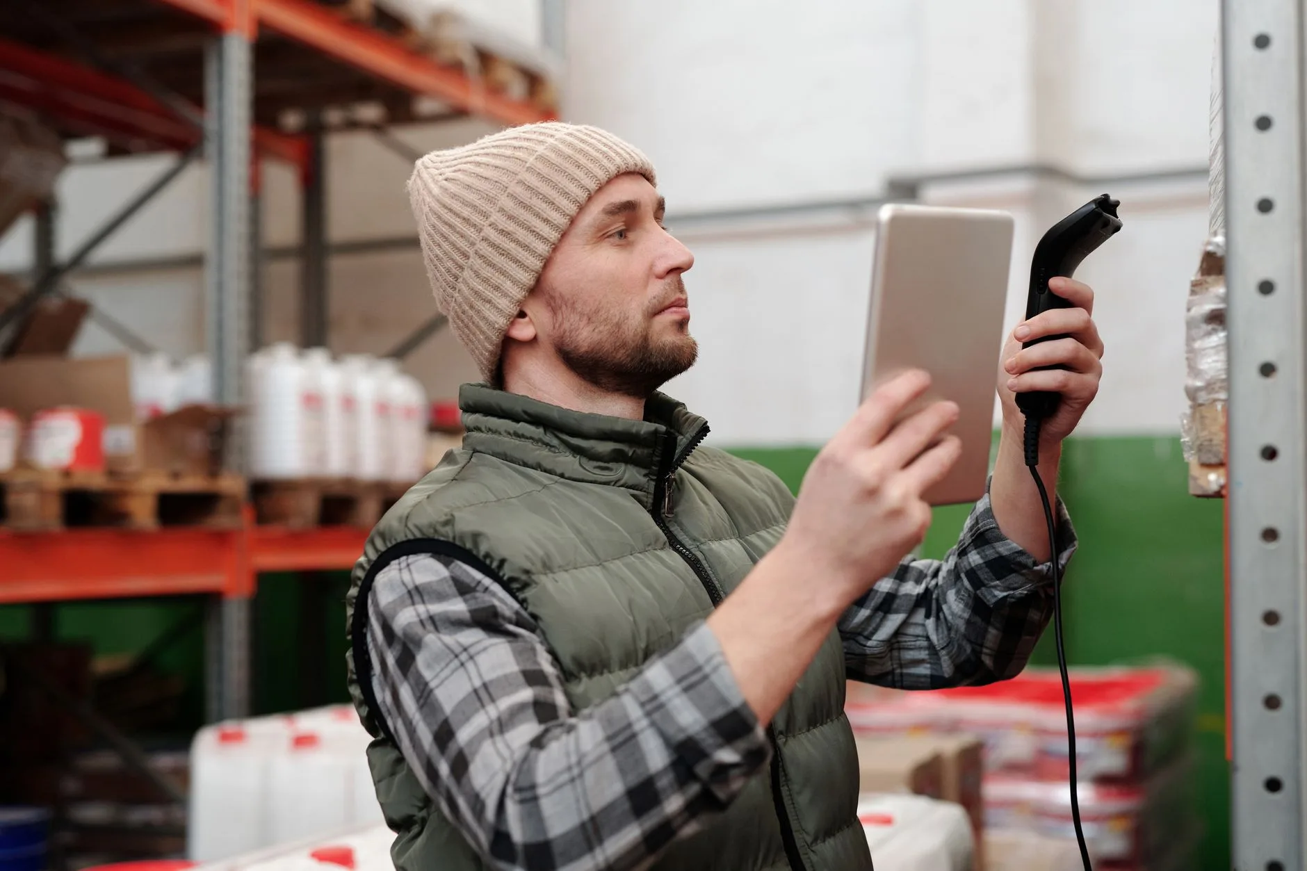 Magasinier scanne un article en rayon et vérifie les stocks sur sa tablette