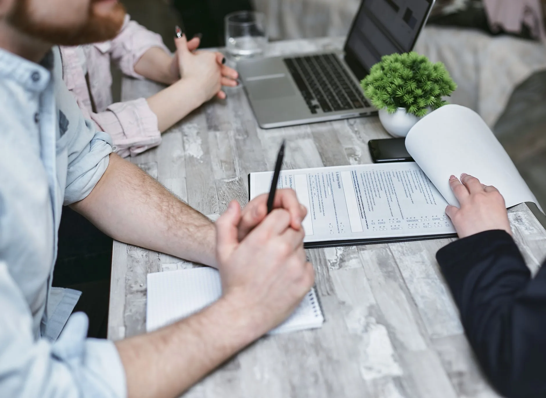 Deux personnes signent un contrat autour d'une table de réunion, ordinateur portable ouvert à côté