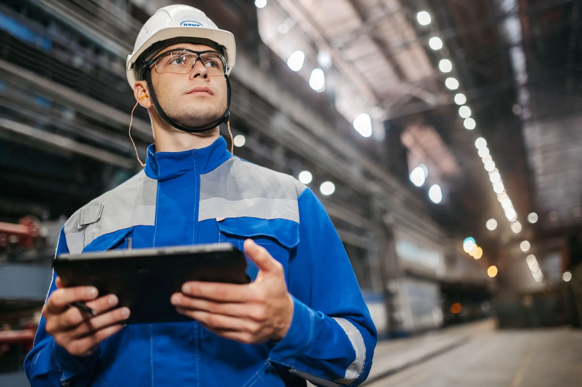 Opérateur en équipement de sécurité consultant une tablette sur une ligne de production