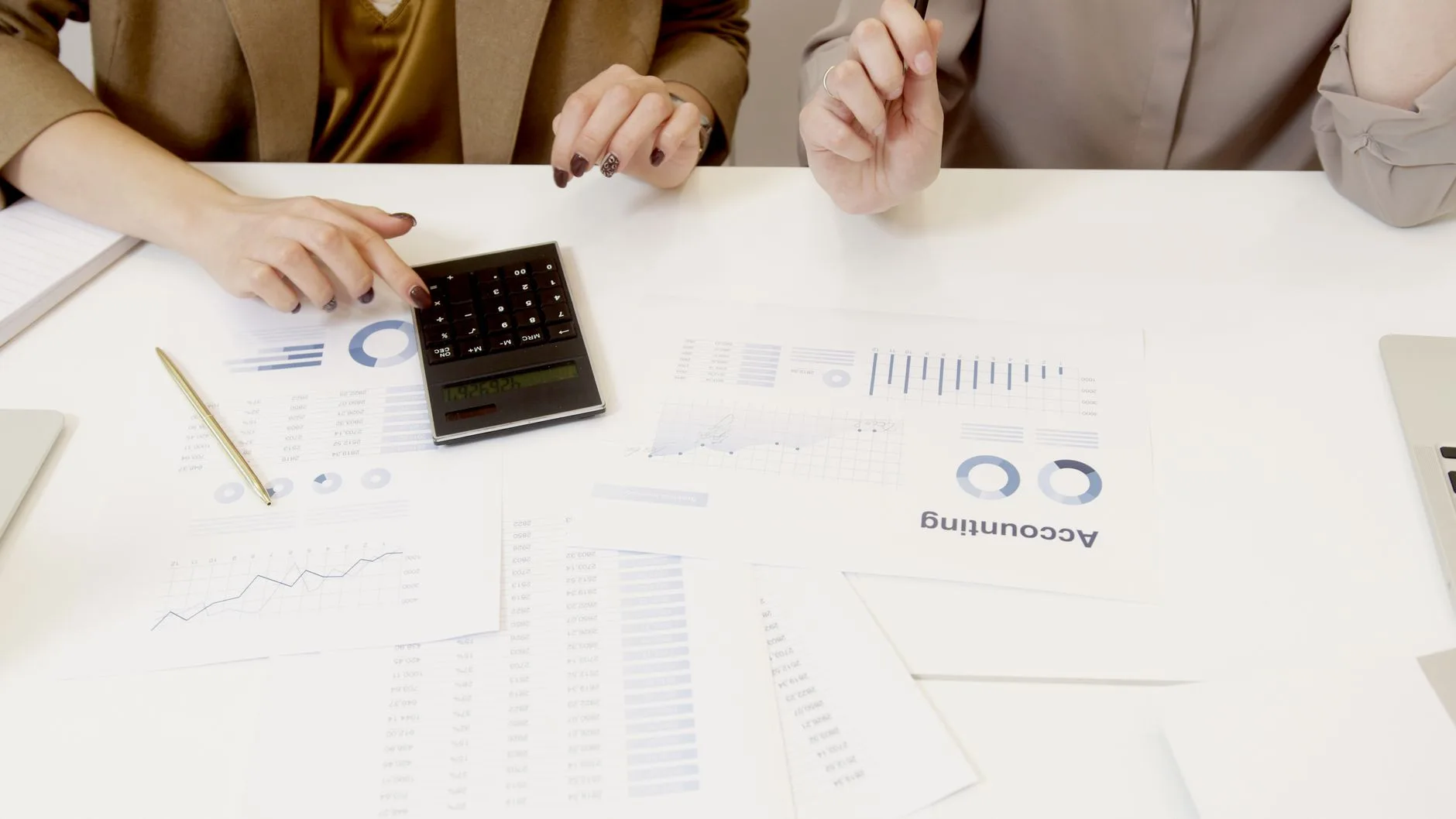 Deux collaboratrices comparent des tableaux de chiffres et une calculatrice sur une table de réunion