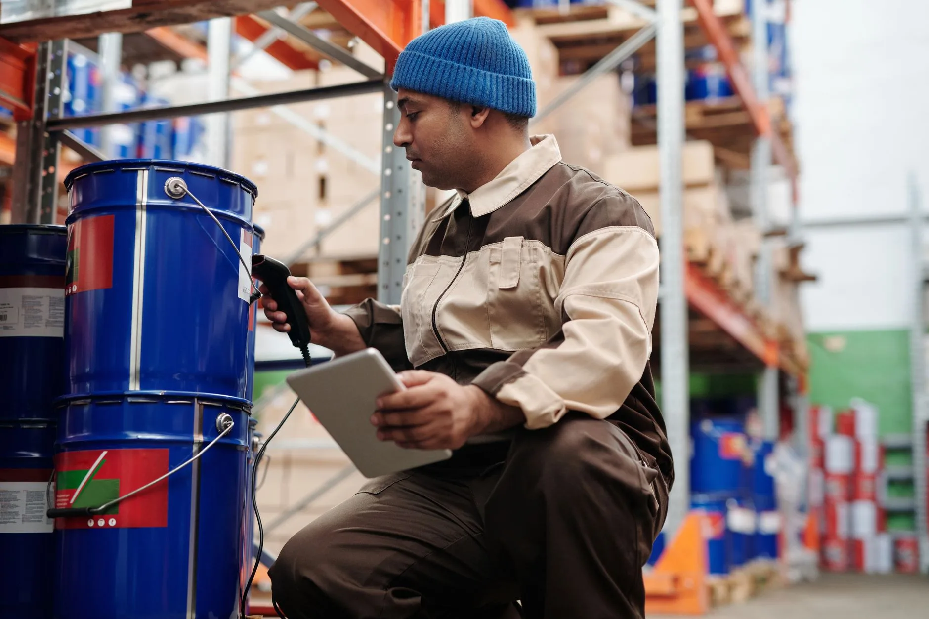 Opérateur logistique scanne une référence avec un terminal mobile et une tablette dans les allées de stockage