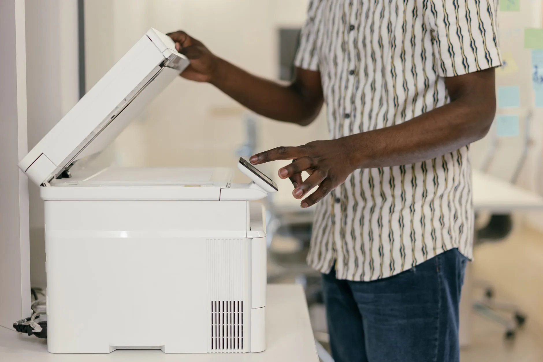 Salarié place une liasse de documents papier sur le scanner d'un copieur de bureau