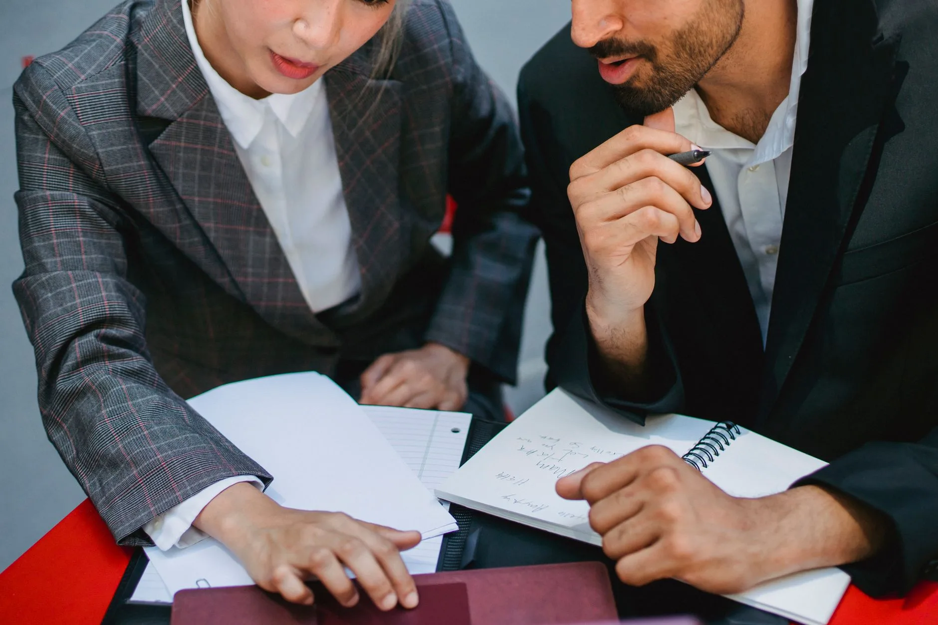 Deux professionnels relisent ensemble des rapports annotés autour d'une table de réunion