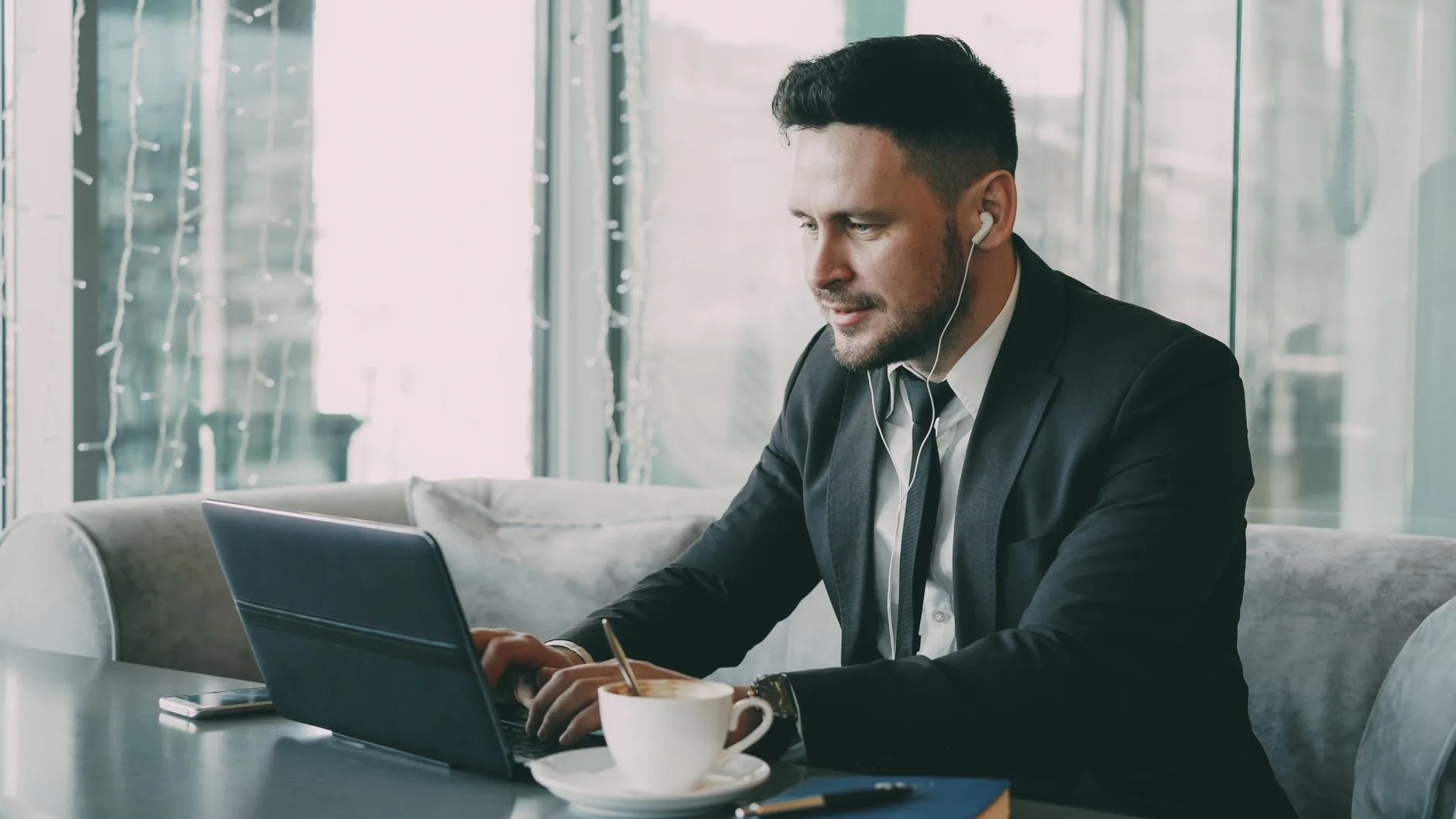 Consultant indépendant travaille sur son ordinateur portable, casque sur les oreilles, dans un espace lumineux