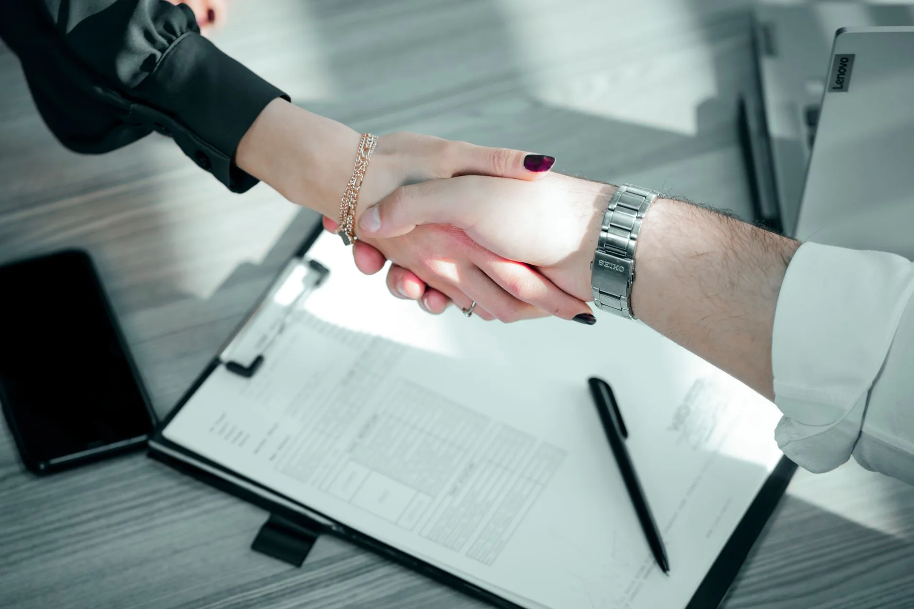 Poignée de main au-dessus d'un contrat signé posé sur une table de réunion