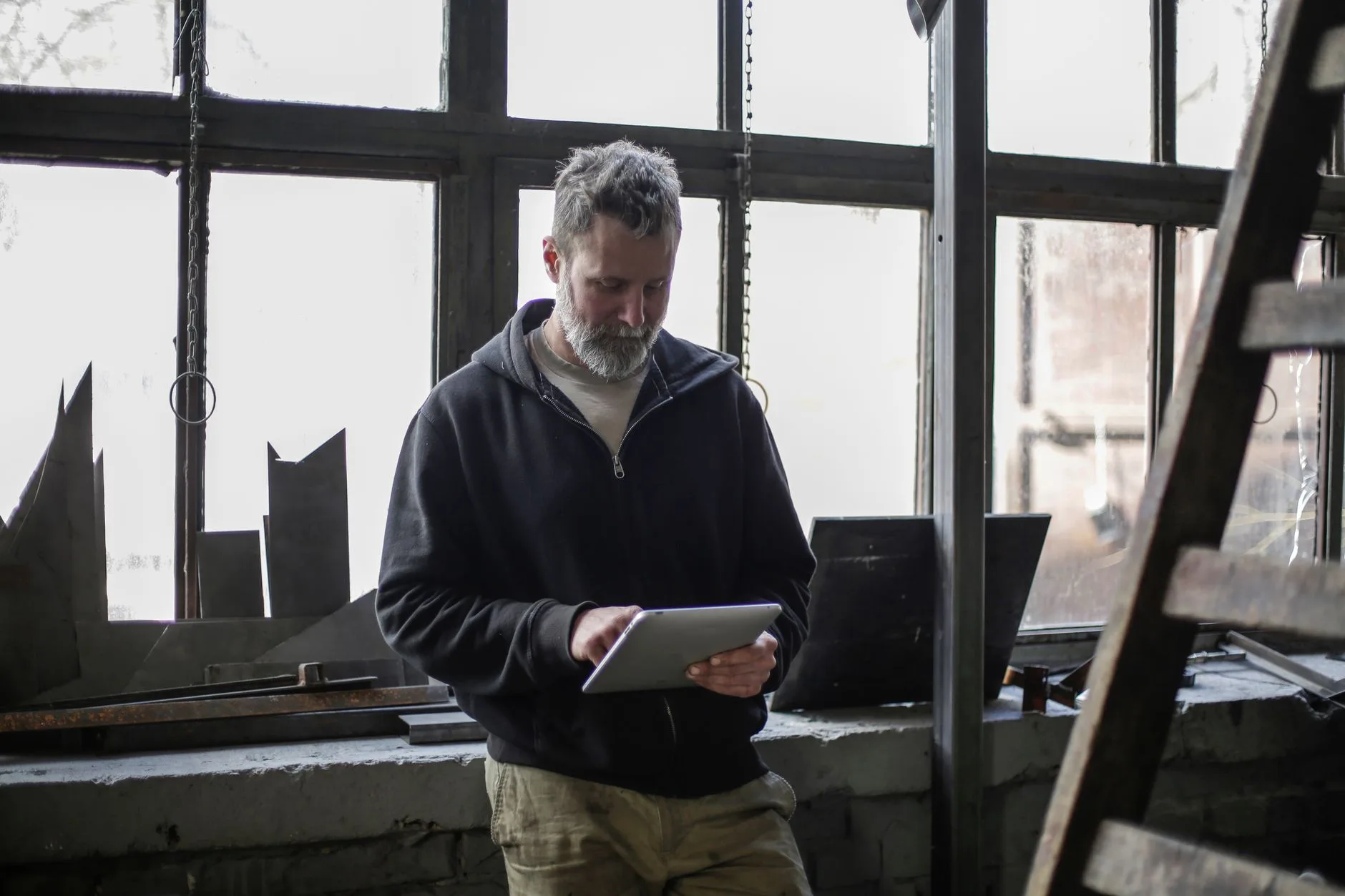Technicien de maintenance consulte sa tablette près d'un poste de travail en atelier
