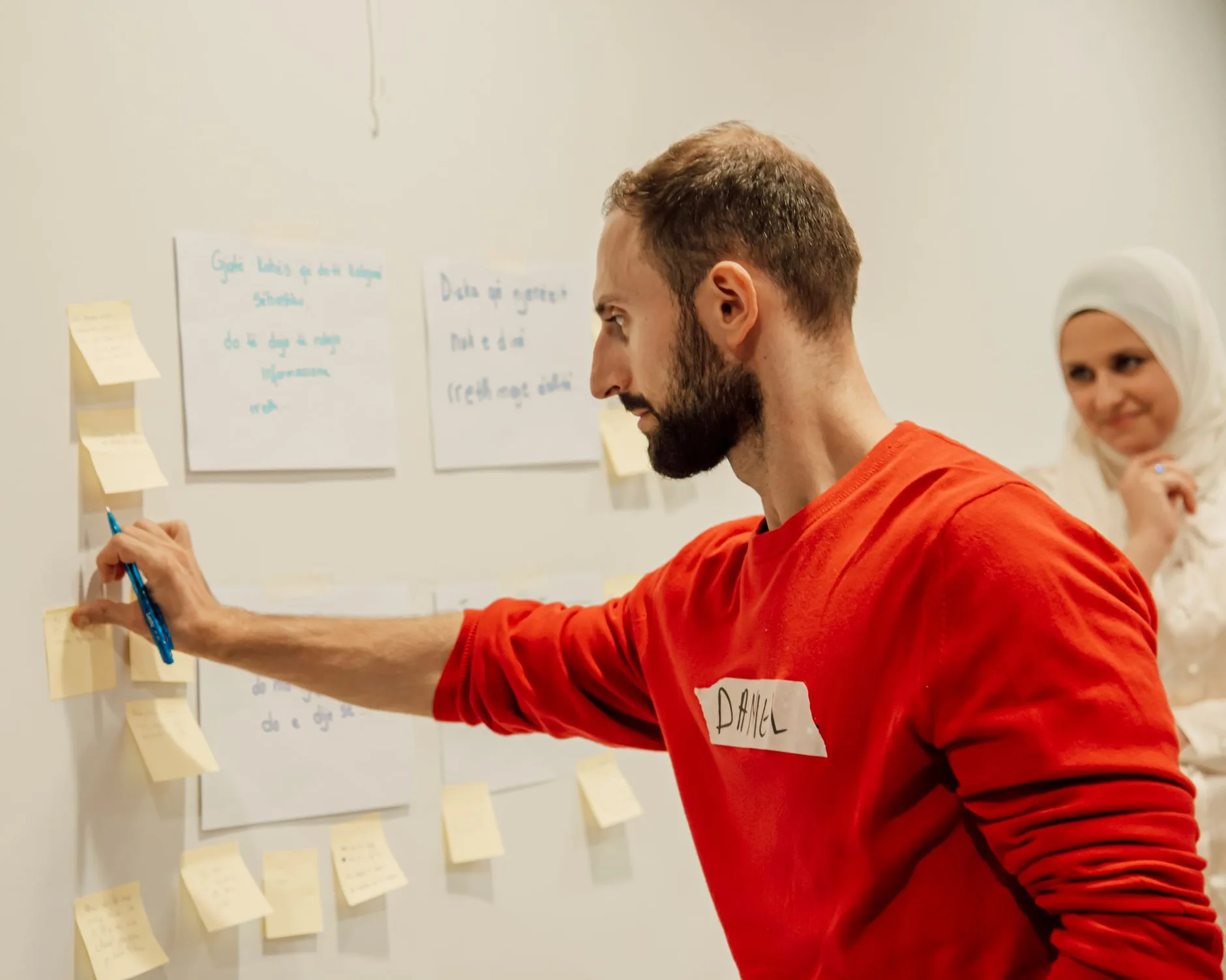 Collaborateur organise des notes adhésives sur un mur pour structurer une méthode de travail en atelier