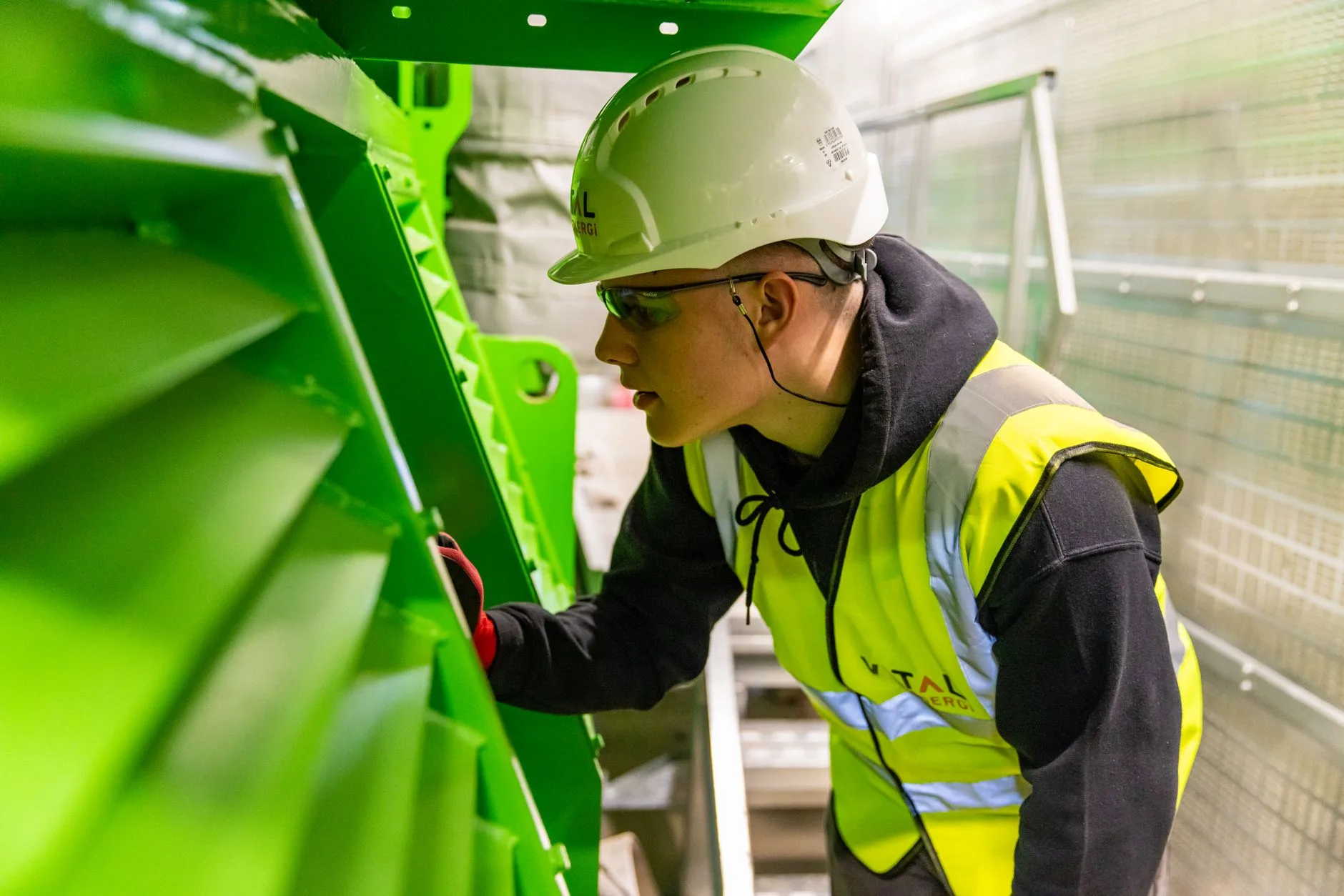 Technicienne de maintenance en gilet de sécurité inspecte une machine industrielle dans un atelier