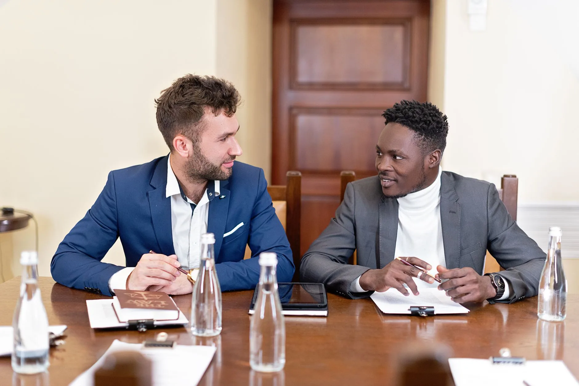 Deux dirigeants en costume discutent face à face autour d’une table de réunion