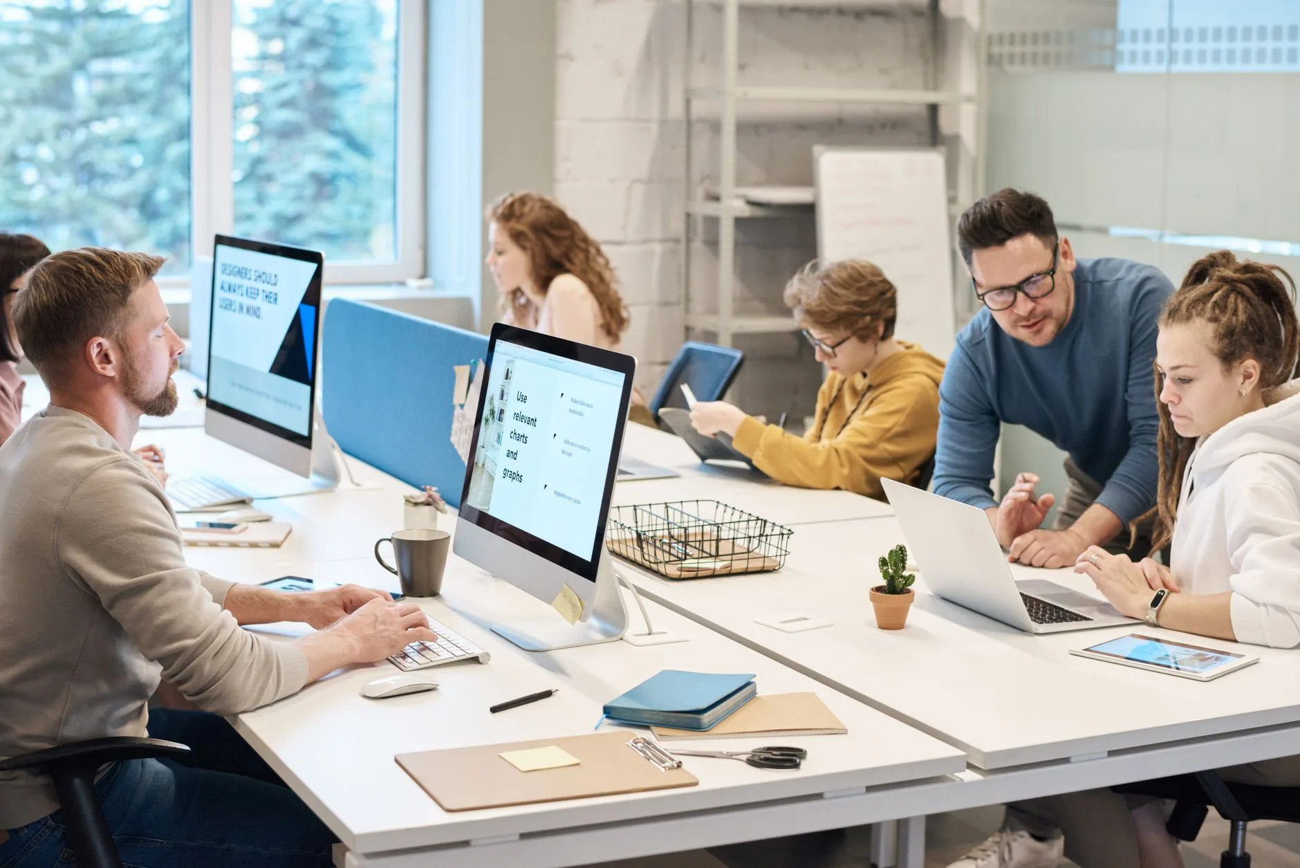 Équipe assise devant des écrans dans un bureau lumineux en open space
