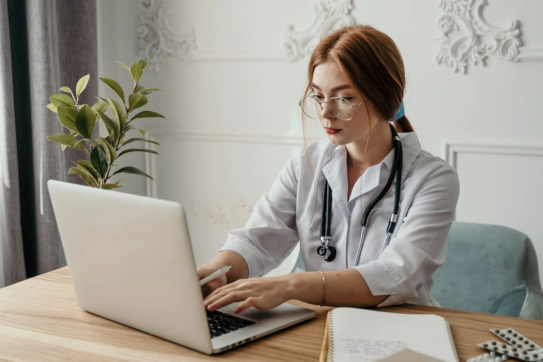 Médecin en blouse blanche saisit un dossier patient sur son ordinateur portable au cabinet