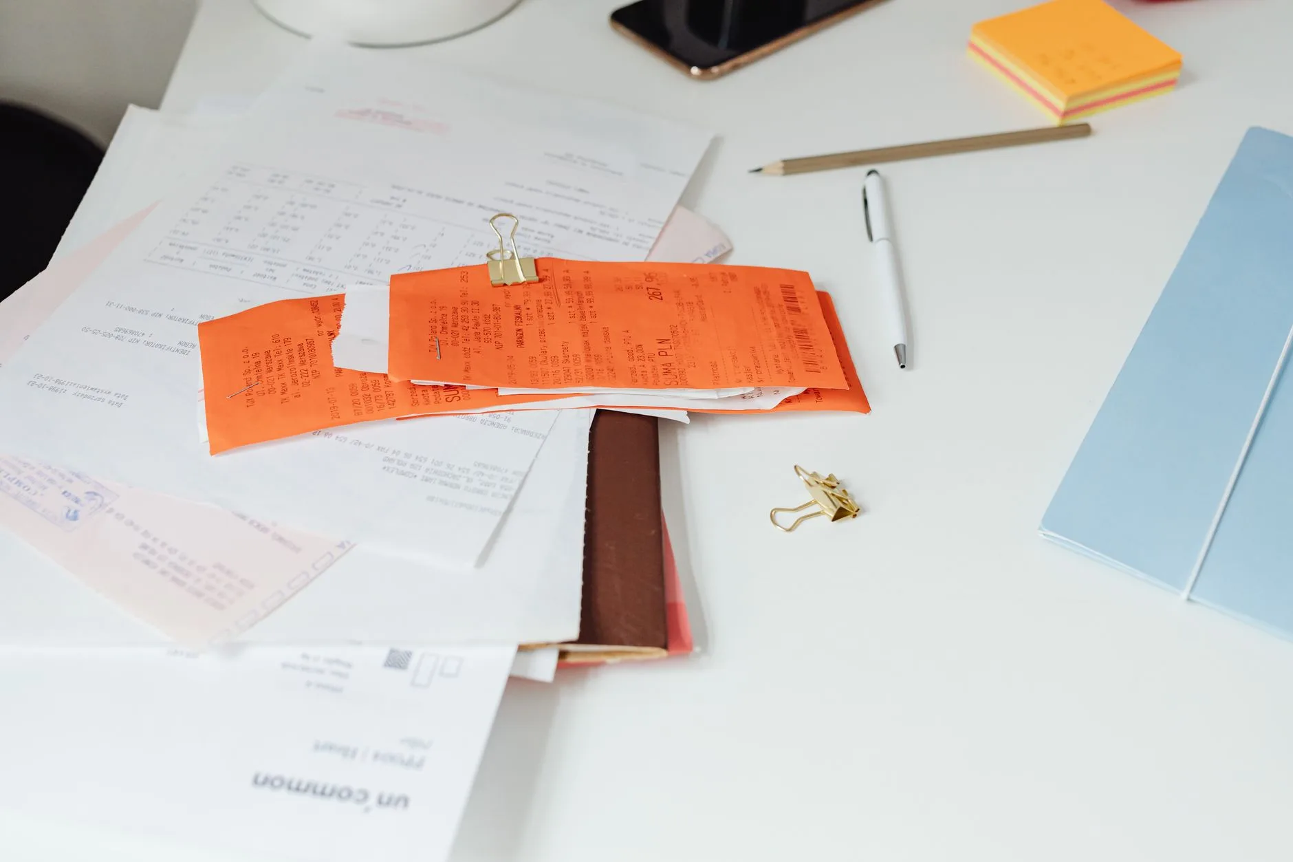 Pile de factures et de reçus en attente de traitement sur un bureau administratif
