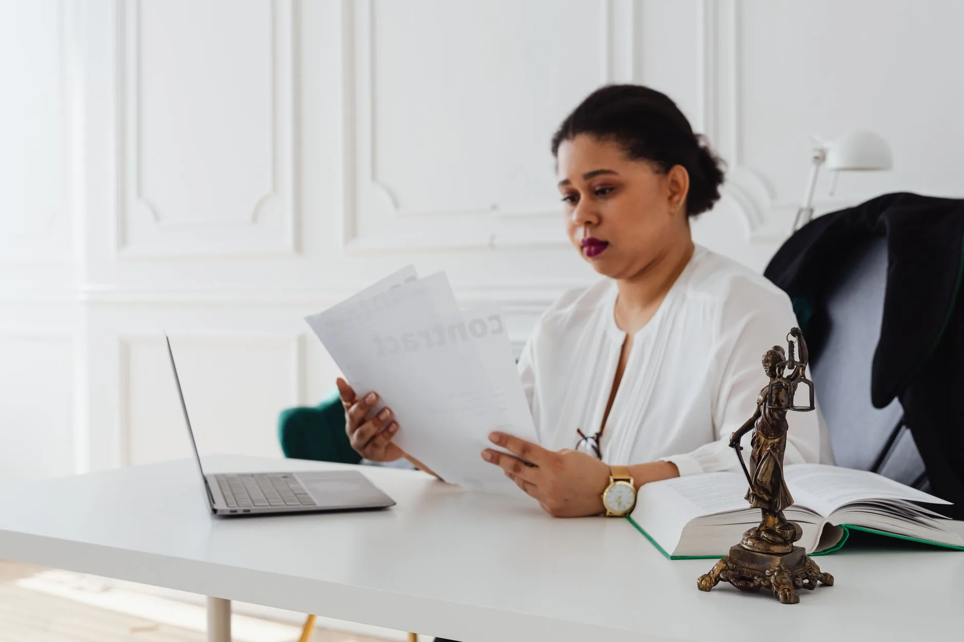 Juriste d’entreprise relit un contrat de conformité à son bureau, ordinateur portable ouvert