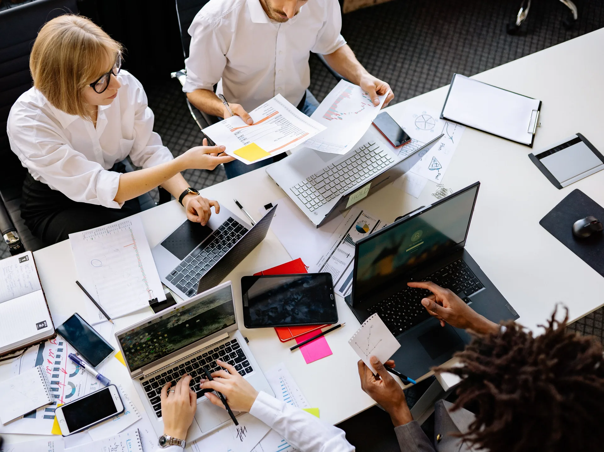 Équipe réunie autour d'une table de travail avec ordinateurs portables et documents