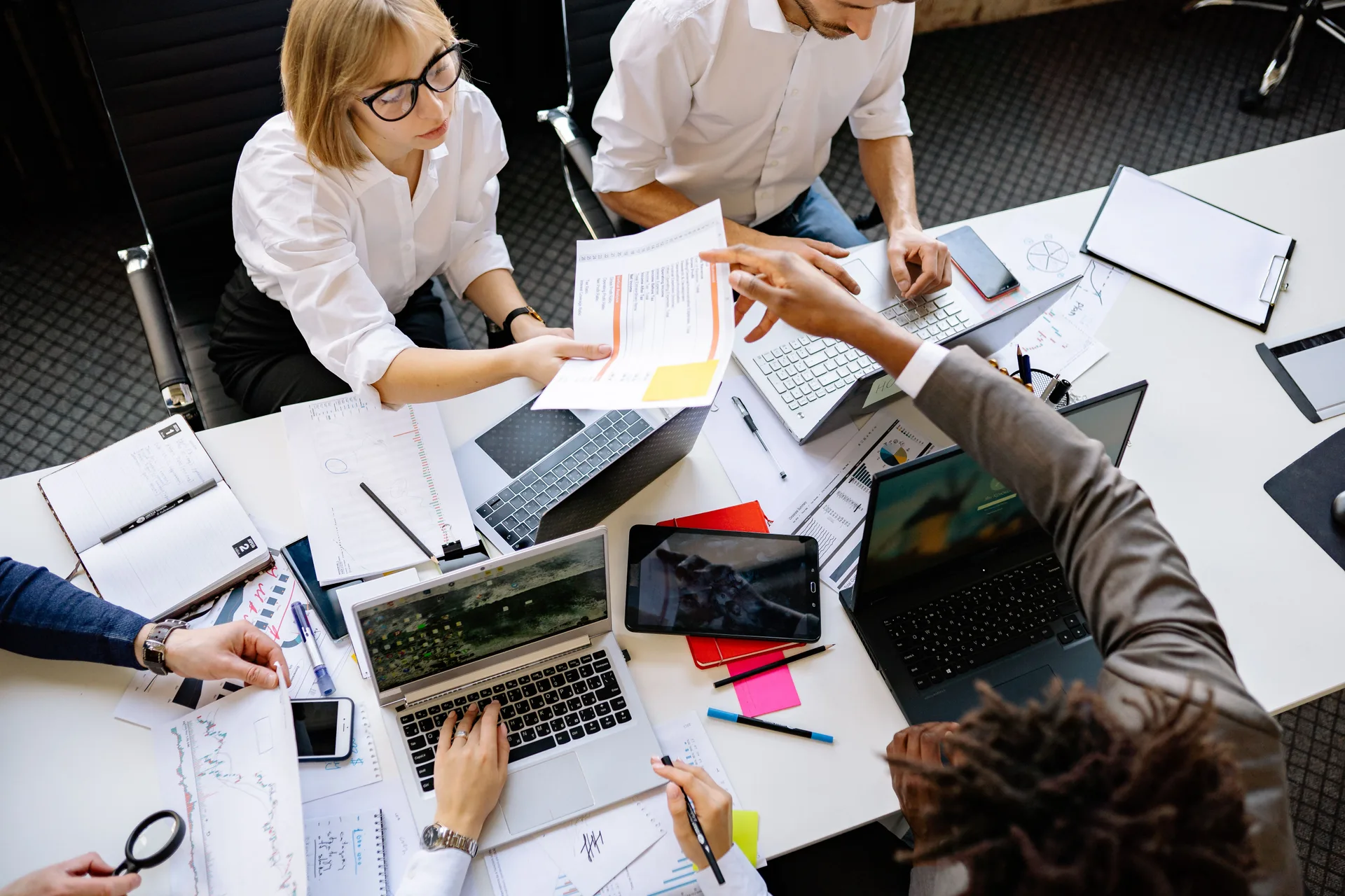 Réunion de cadrage autour d'une table de bureau, avec ordinateurs portables et documents de travail