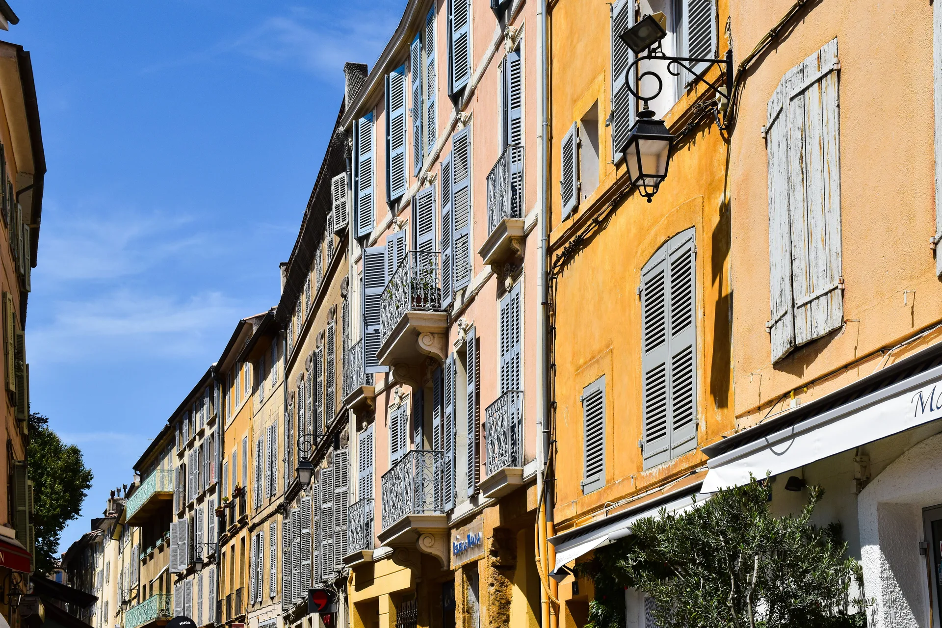 Rue du centre historique d'Aix-en-Provence bordée de façades pastel et de terrasses de café
