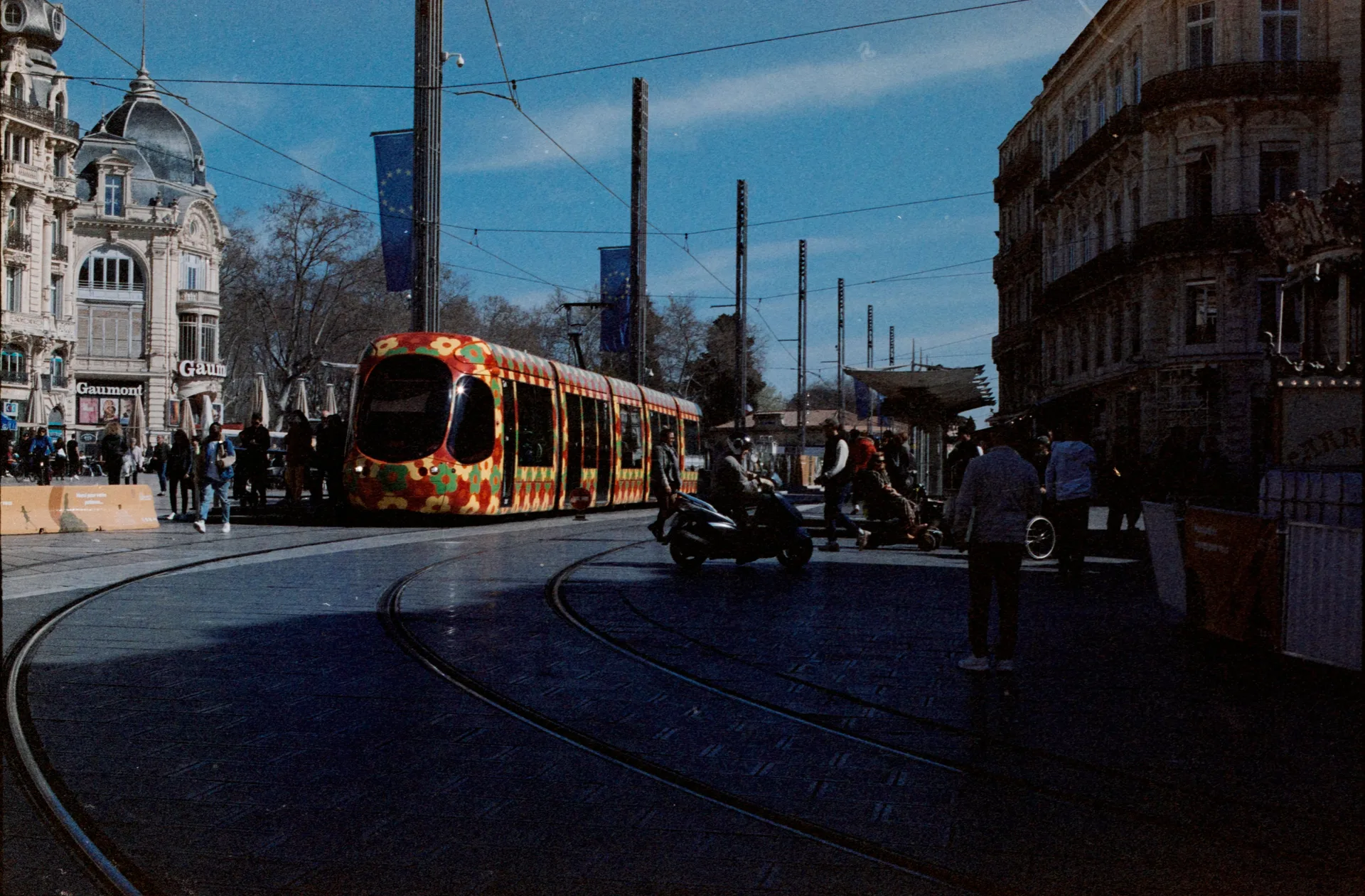 Tramway coloré traversant une rue animée du centre de Montpellier