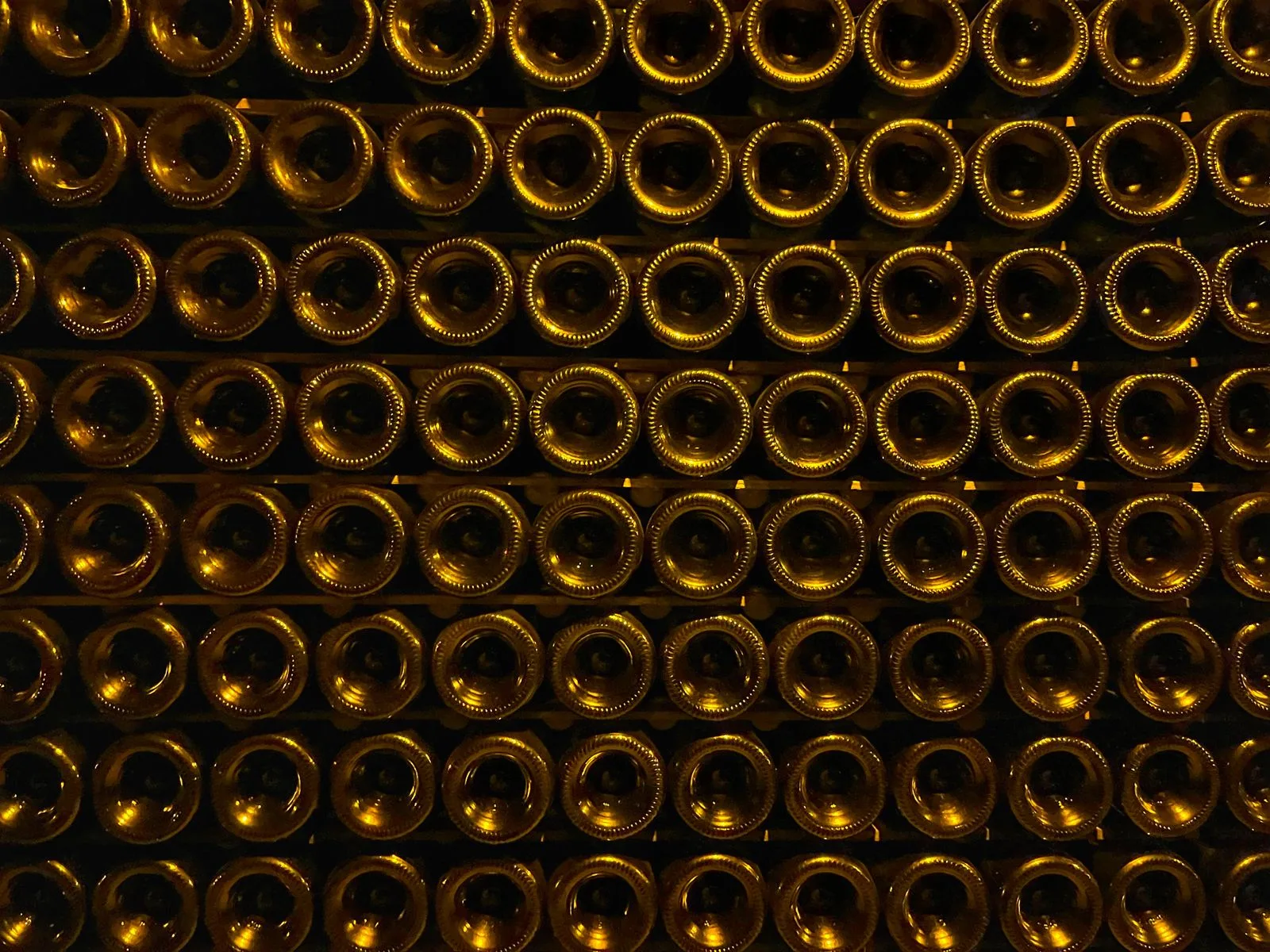 Bouteilles empilées sur lattes dans une cave de champagne faiblement éclairée