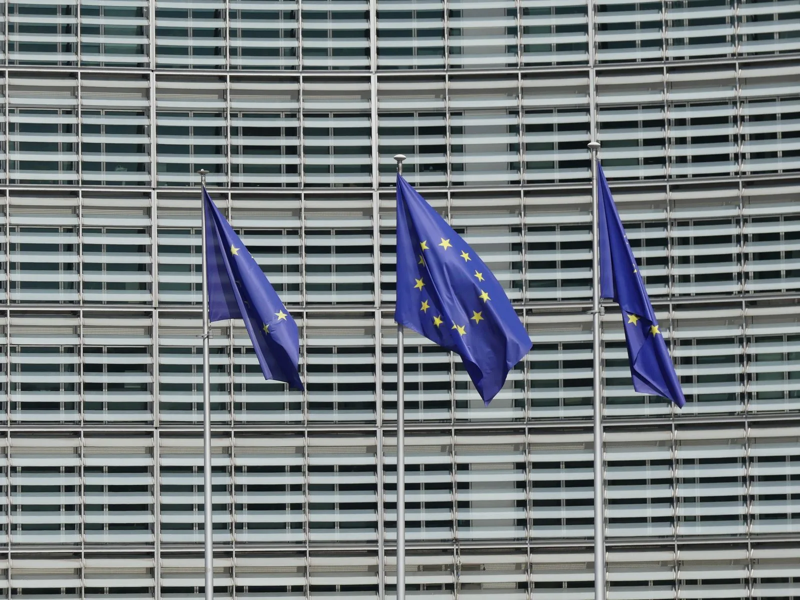 Trois drapeaux européens devant la façade du Berlaymont, siège de la Commission européenne à Bruxelles