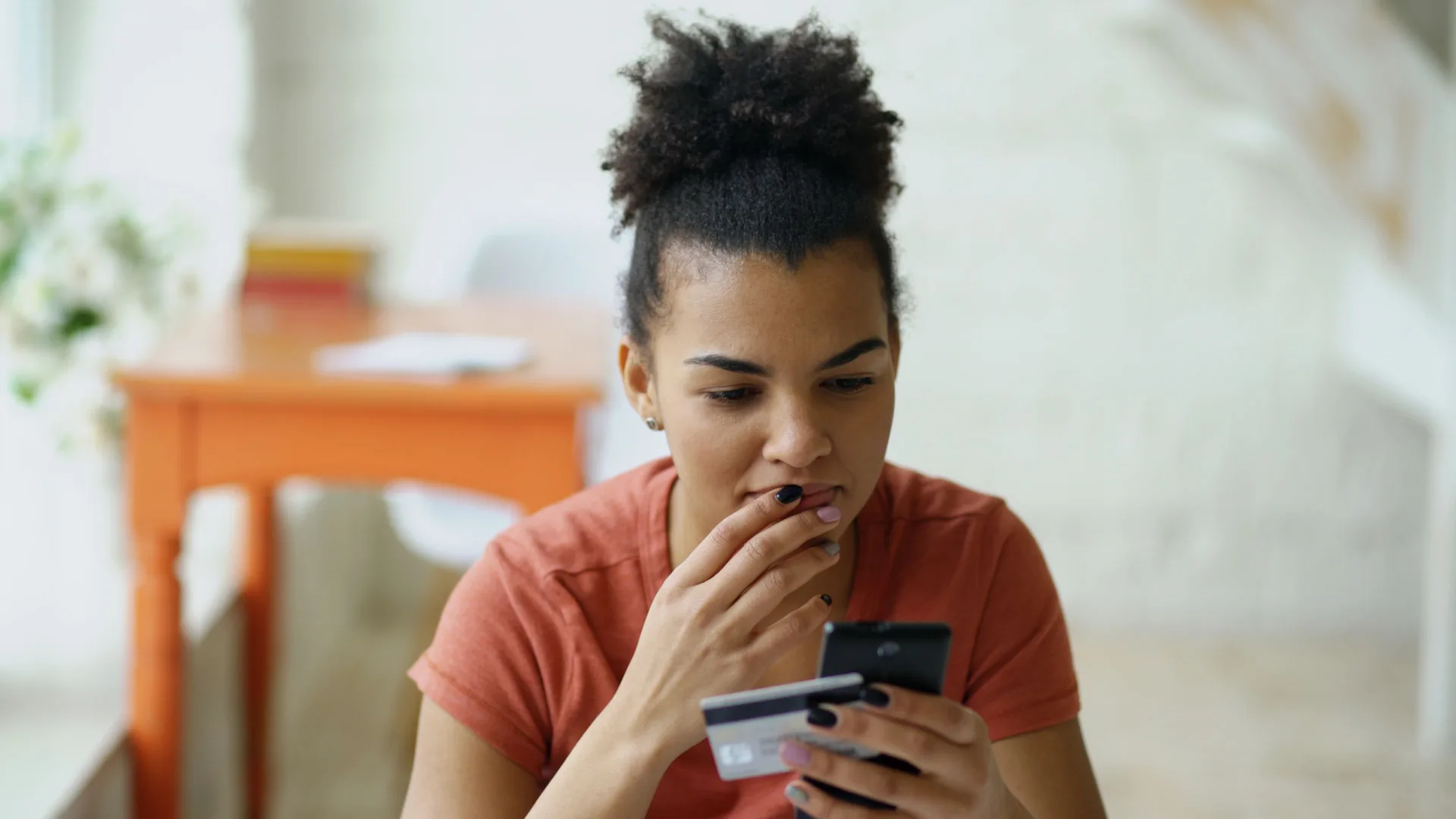 Cliente réglant un achat en ligne avec sa carte bancaire et son téléphone