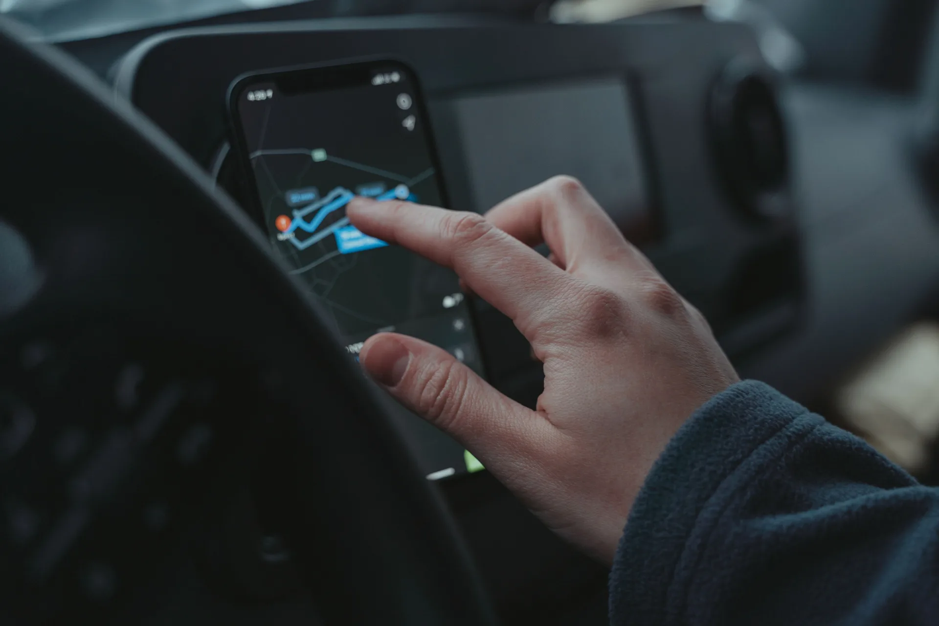 Conducteur consultant un itinéraire GPS sur son smartphone au volant