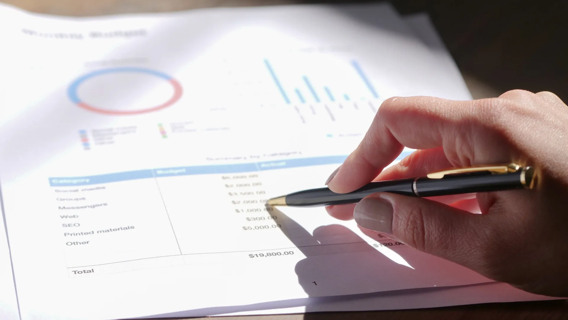 Main pointant un budget détaillé avec graphiques sur un document