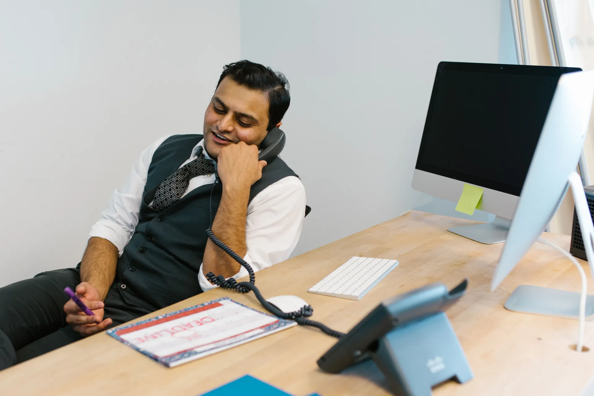 Commercial au téléphone à son bureau devant un ordinateur