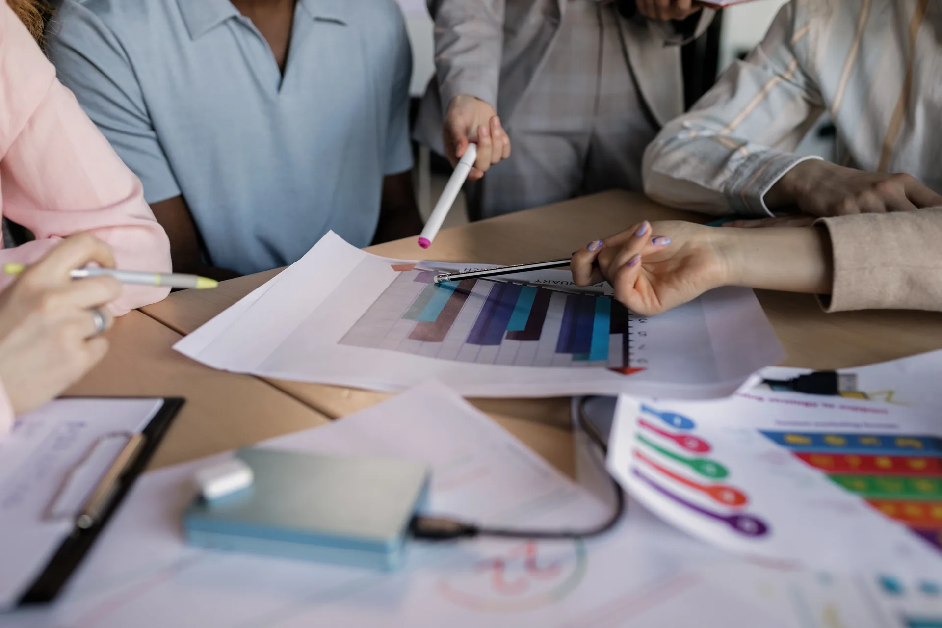 Équipe analysant des graphiques colorés autour d'une table pour affiner sa stratégie