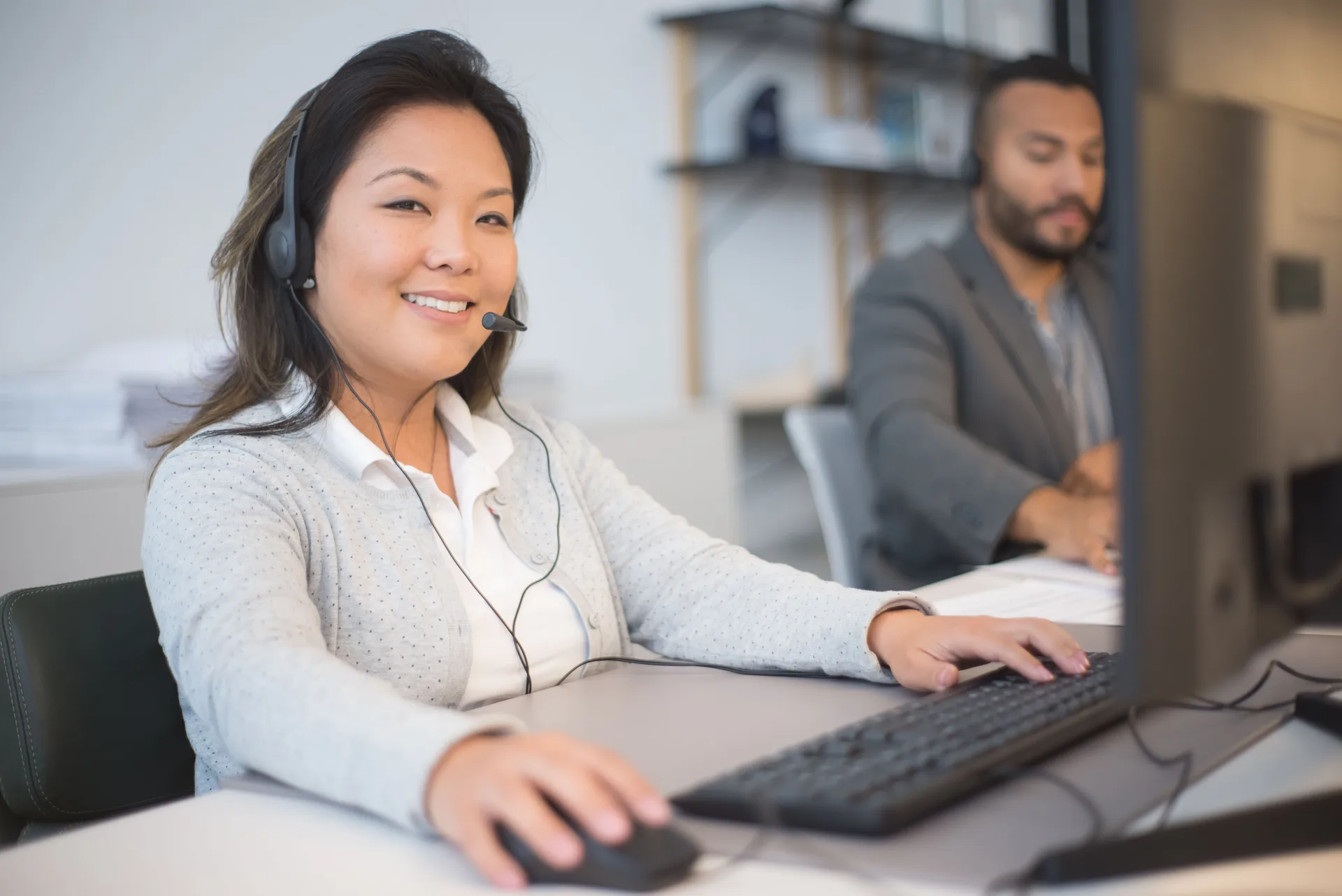 Conseillère souriante au casque devant son ordinateur en centre d'appels
