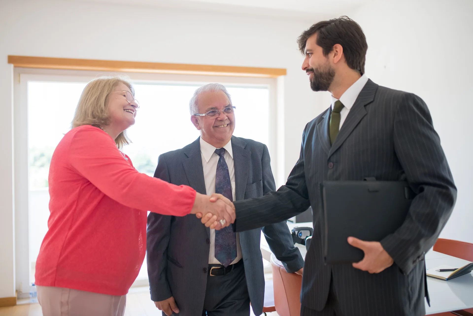 Agent immobilier serrant la main d'un couple de clients satisfaits