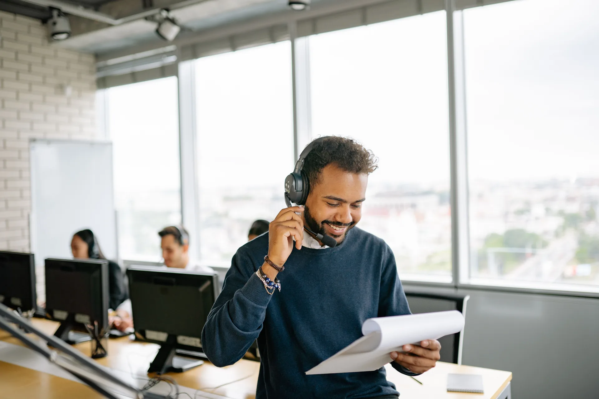 Conseiller client au casque lisant un document dans un centre d'appels